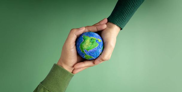Journée mondiale de la Terre Concept. Énergie verte, ESG, ressources renouvelables et durables. Protection de l'environnement. Hands of People Embrassing a Handmade Globe ". Protéger la planète ensemble. Vue du dessus - Photo, image
