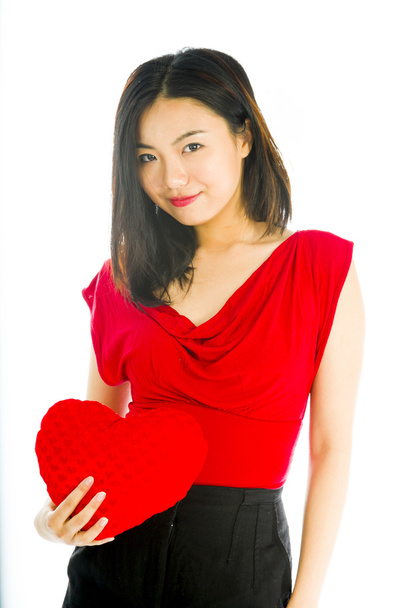 Portrait d'une jeune femme tenant un coussin en forme de coeur
 - Photo, image