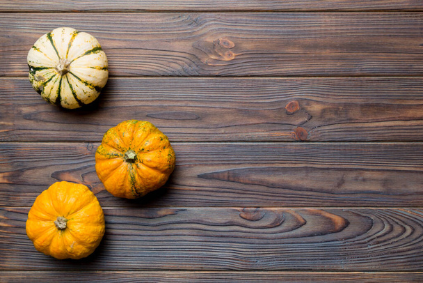 Autumn composition of little orange pumpkins on colored table background. Fall, Halloween and Thanksgiving concept. Autumn flat lay photography. Top view vith copy space. - Zdjęcie, obraz
