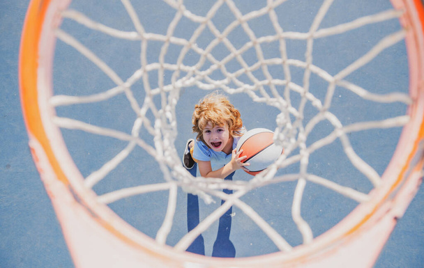 Amazed kid playing basketball holding ball with happy face - Foto, immagini
