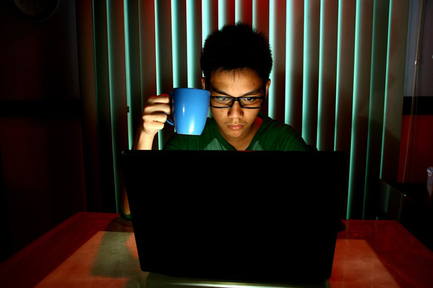 Jovem adolescente segurando uma caneca de café na frente de um computador portátil
 - Foto, Imagem