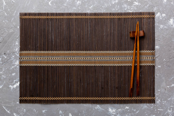 Two chopsticks and bamboo mat on cement background. Top view, copy space. - Foto, immagini