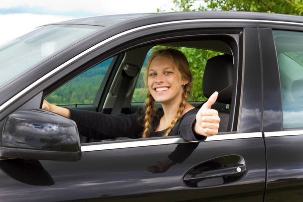 Jovem mulher em um carro com o polegar para cima - Foto, Imagem