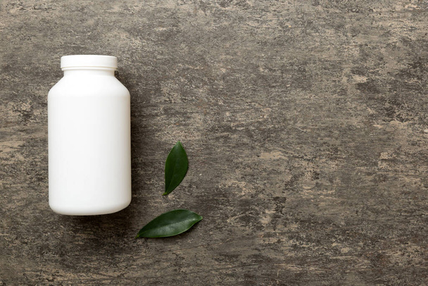 supplement pills with medicine bottle health care and medical top view. Vitamin tablets. Top view mockup bottle for pills and vitamins with green leaves, natural organic bio supplement, copy space. - Photo, Image