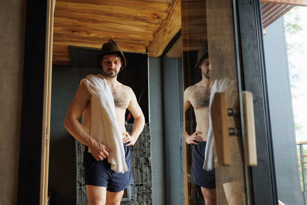 Uomo muscoloso nella sauna con un asciugamano sulle spalle - Foto, immagini