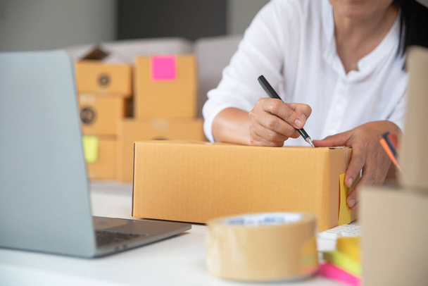 Primo piano della scrittura manuale dell'imprenditore sulle scatole dei pacchi per consegnare i prodotti ai clienti a casa. - Foto, immagini