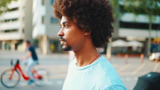 Close-up of young African American man in  light blue t-shirt is standing on crosswalk.  - Φωτογραφία, εικόνα