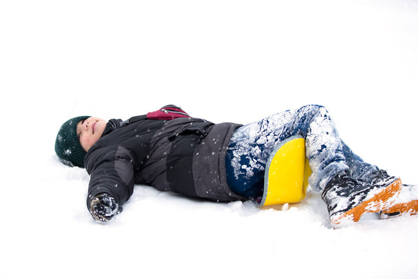 Dziecko w zimie. Chłopiec upadł na sanki i leży w śniegu.. - Zdjęcie, obraz