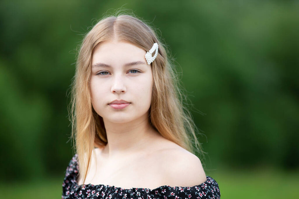 Retrato de uma menina bonita com cabelos longos em um fundo de verão. O rosto de uma adolescente de cabelos claros. - Foto, Imagem