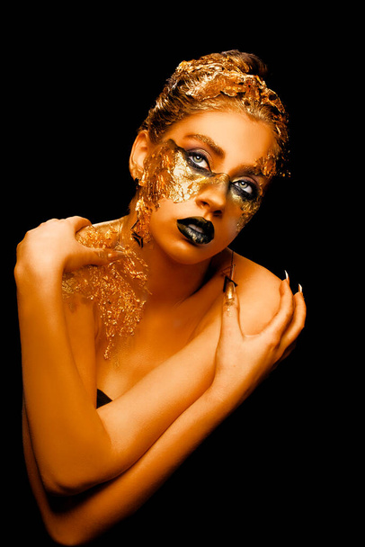 Fashion art Golden skin. Girl Model with Festive Golden Glamor Brilliant Professional Makeup. Creative makeup with golden foil. - Photo, Image