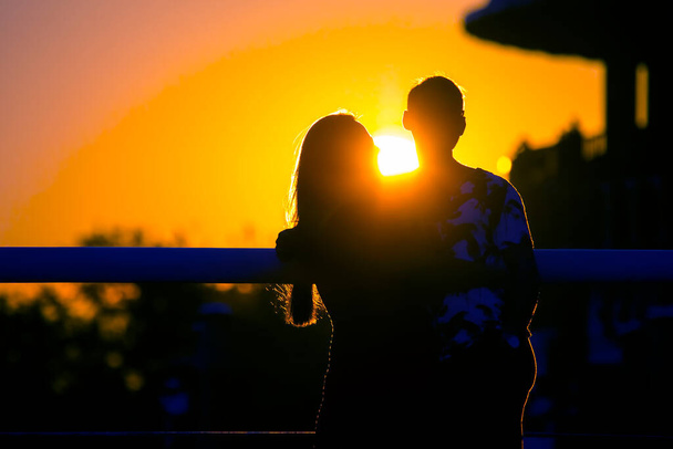 Silhouette of two people in love against the backdrop of the setting sun. Romance in relationships and nature - Photo, Image