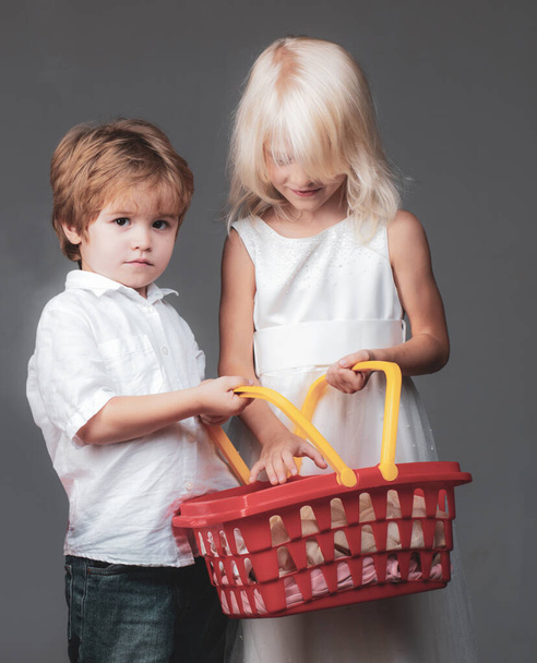 Couple kids hold plastic shopping basket toy. Mall shopping. Buy with discount. Buy products. Play shop game. Cute buyer customer client hold shopping cart. Girl and boy children shopping. Kids store. - Photo, image