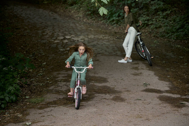 Maman et fille font du vélo dans le parc. Enfants vacances d'été concept - Photo, image