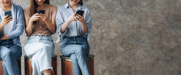 女性のグループは、部屋の行には、携帯電話で遊んで座っている。スマートフォン通信ツールを使ってソーシャルメディアを再生し、アプリを通じて人と話すメッセージを送るというコンセプト. - 写真・画像