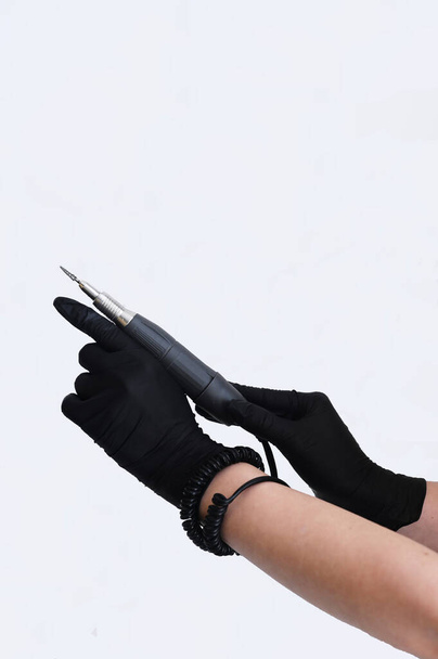 Female hands in black gloves with a nail cutter on a white background - Foto, Imagem
