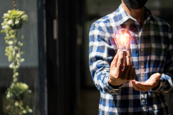 Man holding a light bulb, new ideas, technological innovations and creativity. with a sparkling light bulb Concept with innovation and inspiration - Fotoğraf, Görsel