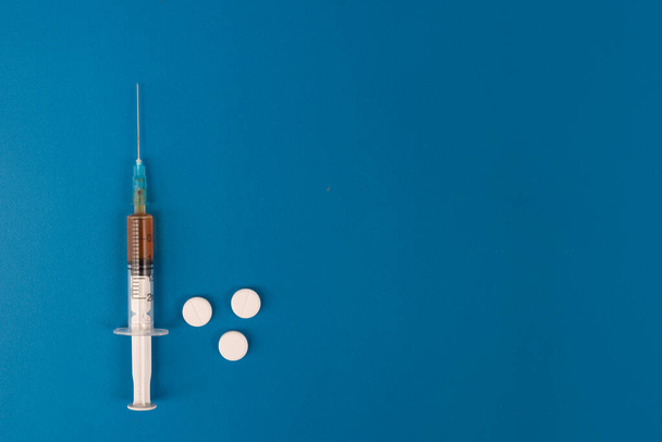 Disposable medical plastic syringe with vaccine on a blue background. - Valokuva, kuva