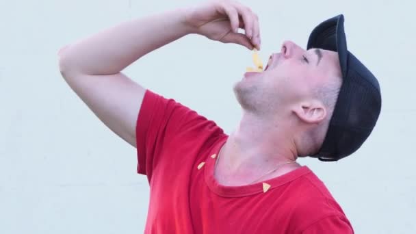 Retrato de cerca de un hombre con una camiseta roja comiendo papas fritas en la calle 4 K - Metraje, vídeo
