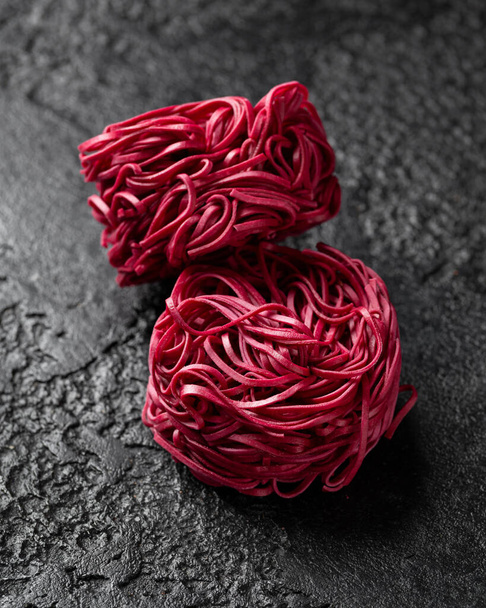 Dry beetroot noodles on rustic dark background - Фото, зображення