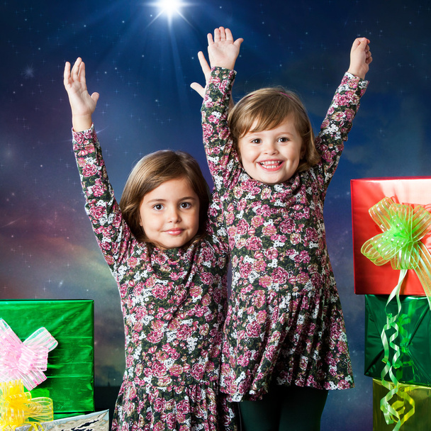 Two happy kids raising hands next to presents. - Photo, Image