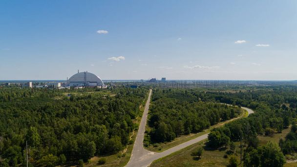 Luftaufnahme von Wäldern und Straßen in der Nähe des Atomkraftwerks Tschernobyl. Drohnenschuss im Sommer. Strahlung, Sarkophag - Foto, Bild