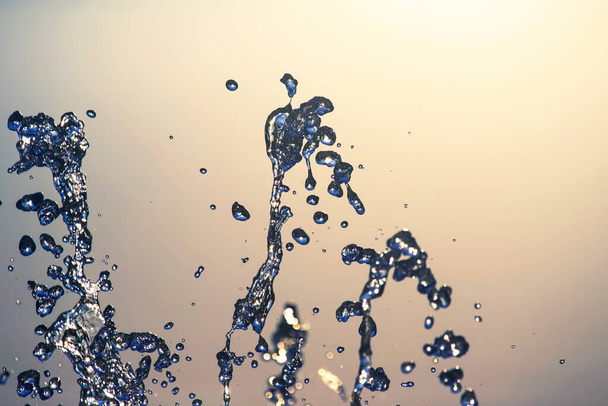 vliegende druppels waterfontein close-up op de achtergrond van de lucht - Foto, afbeelding