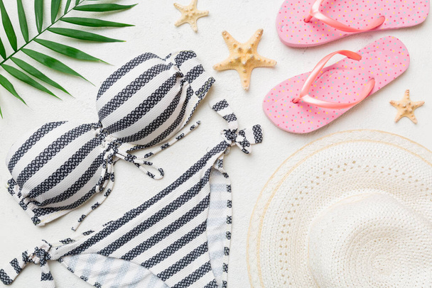 Woman swimwear and beach accessories flat lay top view on colored background Summer travel concept. bikini swimsuit, straw hat and seasheels. Copy space Top view. - Fotó, kép