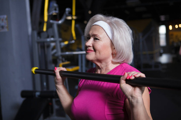 Close-up de uma mulher idosa alegre gostando de trabalhar no ginásio, fazendo imprensa no peito - Foto, Imagem