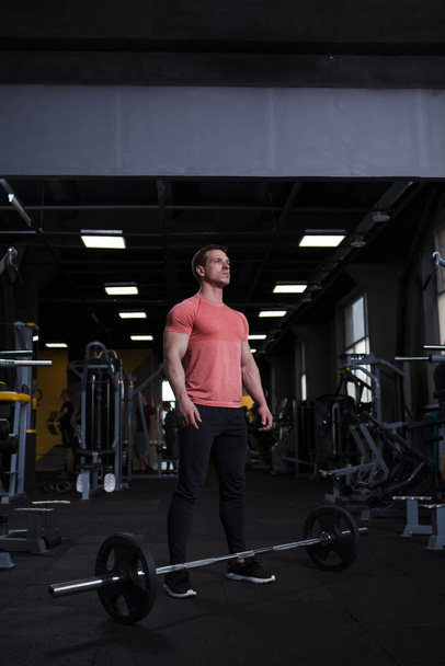 Vertical shot of a strong confident male athlete preparing for barbell workout - Foto, imagen