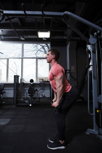 Aufnahmen in voller Länge eines Sportlers, der in einem Crossover-Fitnessgerät Rückenmuskeln trainiert - Foto, Bild