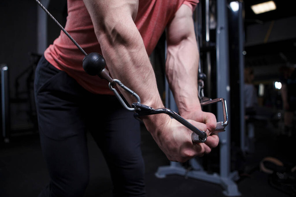 Muscular arms with veins close up, bodybuilder exercising in cable crossover gym machine - Foto, afbeelding