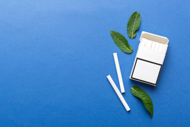 Pack of menthol cigarettes and fresh mint on colored table, Menthol cigarettes top view flat lay. - Foto, immagini