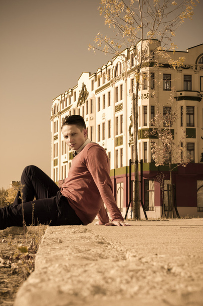 handsome casual man sitting on the sidewalk in  old city - Foto, imagen