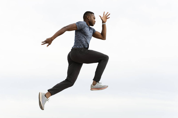 Vue complète des athlètes multiraciaux homme courir et sauter à la plage avec ciel nuageux. Concept de sport et de loisirs  - Photo, image