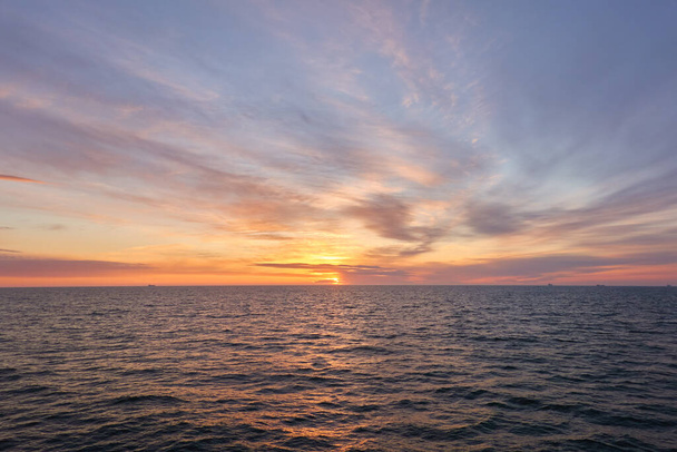 Балтійське море на заході сонця. Драматичне небо, блакитні і рожеві сяючі хмари, м'яке золоте сонце, полярне сонце. Нікчемний мрійливий морський мис, хмарний пейзаж, природа. Панорамний вид - Фото, зображення