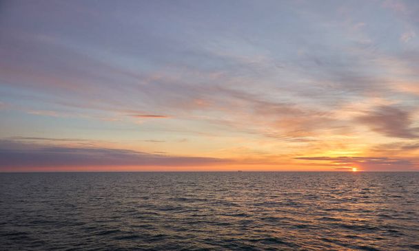 Itämeri auringonlaskun aikaan. Dramaattinen taivas, sininen ja vaaleanpunainen hehkuva pilvet, pehmeä kultainen auringonvalo, keskiyön aurinko. Viehättävä unenomainen merimaisema, pilvi, luonto. Panoraamanäköala - Valokuva, kuva