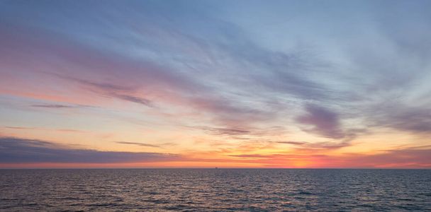 Baltské moře při západu slunce. Dramatická obloha, modré a růžové zářící mraky, měkké zlaté sluneční světlo, půlnoční slunce. Soumrak, letní noc. Malebná pohádková krajina, přímořská krajina, příroda. Panoramatický pohled - Fotografie, Obrázek