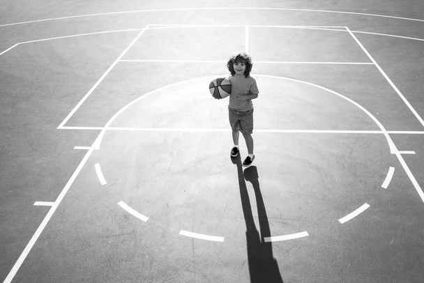 Basketball kids game. Cute little child boy holding a basket ball trying make a score - Φωτογραφία, εικόνα