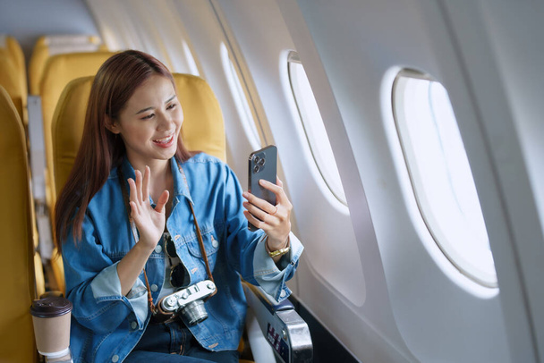 Reise, Tourismusgeschäft, Porträt einer Frau, die ihr Handy-Selfie im Flugzeug benutzt, um ein Profilbild von sich zu posten. - Foto, Bild
