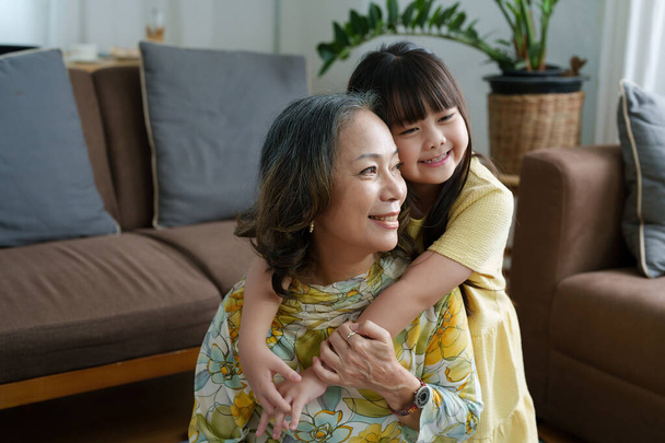 Ασιατικό πορτρέτο, η γιαγιά και η εγγονή κάνουν ψυχαγωγικές δραστηριότητες και αγκαλιάζονται για να δείξουν την αγάπη και τη φροντίδα τους ο ένας για τον άλλο. - Φωτογραφία, εικόνα