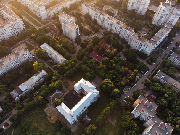 太陽の光で緑の夏の住宅街の学校の建物の空中ビュー。朝の街の通りの上を飛ぶ。ハリコフのツリートップビュー,ウクライナ - 写真・画像