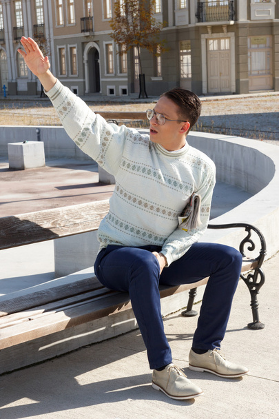 man with glasses in white sweater siting on bench and holding ne - Фото, изображение