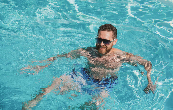 Summertime vacation at pool. Summer weekend. Handsome man in swimmingpool water. Pool spa resort - Fotó, kép
