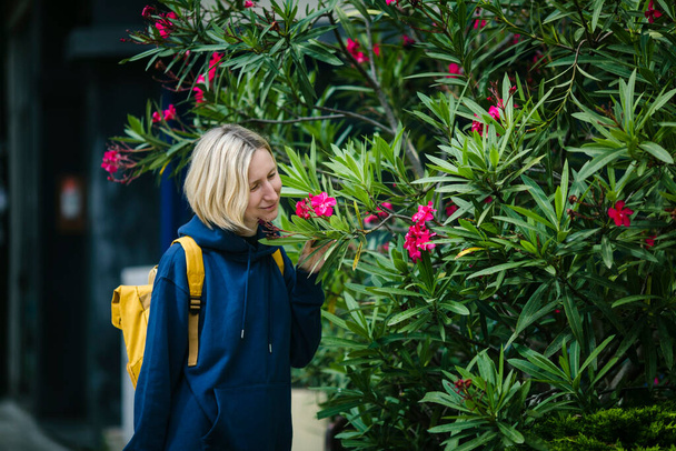Μια γυναίκα μυρίζει τα ανθισμένα φυτά στο πάρκο.. - Φωτογραφία, εικόνα