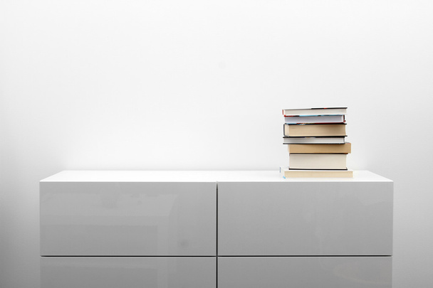 weiße Kommode mit Bücherstapel im hellen Minimalismus-Interieur - Foto, Bild