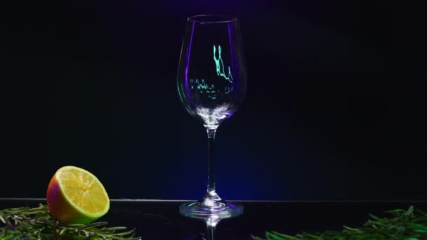 Κοντινό πλάνο του ρίχνει πράσινο ποτό κοκτέιλ σε ένα διαφανές ποτήρι στέκεται στον πάγκο μπαρ. Κλιπ μετοχών. Bar counter διακοσμημένο με πράσινα φύλλα και πορτοκαλί - Πλάνα, βίντεο