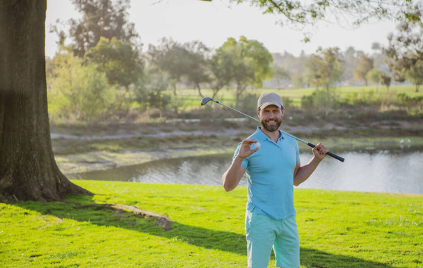 Portrait of happy smilin golfer hitting golf shot with club on course - Foto, immagini