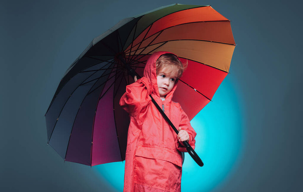 Child advertise your product and services. Handsome little guy in preparing for Autumn. Cute little child wearing in autumn clothes on autumn rain day. Cheerful boy in raincoat with colorful umbrella - Zdjęcie, obraz