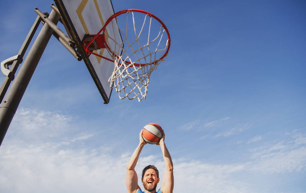 Man basketball player sportsman in shirt and shorts hold basketball ball on urban background. Sport motivation concept - Fotografie, Obrázek