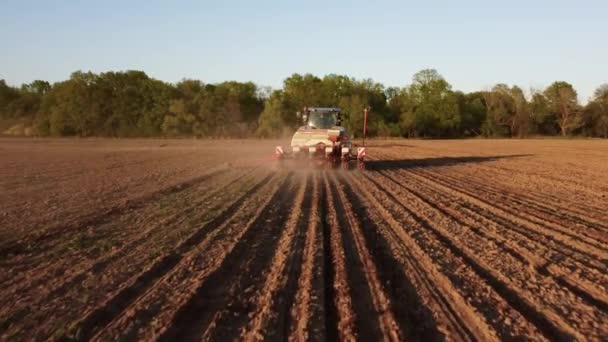 Légi felvétel a kék traktorról a tavaszi mezőn. A vetés előkészítésének ideje. Lövöldözés drónról, amint traktor felett repül terepen, elkészített talajjal ültetésre. Mezőgazdasági koncepció. Vidéki táj. - Felvétel, videó